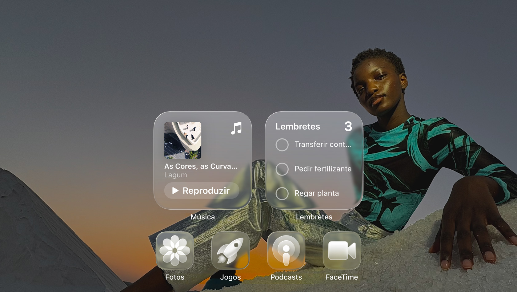 Tela em Liquid Glass com ícones de apps transparentes, como Apple Music, Lembretes, Fotos, Jogos, Podcasts e FaceTime, que criam um efeito de refra??o na imagem de fundo.