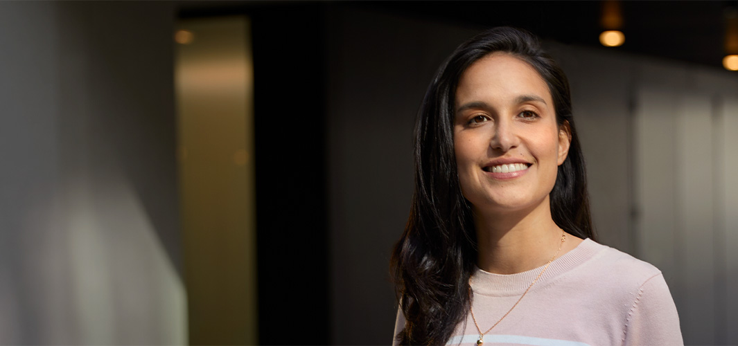 Camila stojí v?kancelá?ském prostoru a?usmívá se.