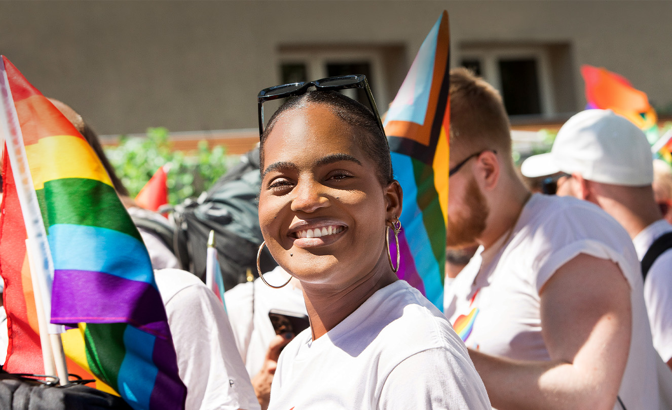 Usmívající se zaměstnanec Apple na akci Apple Pride v?davu zaměstnanc? s?vlajkami Pride a?v?tri?kách Pride. 