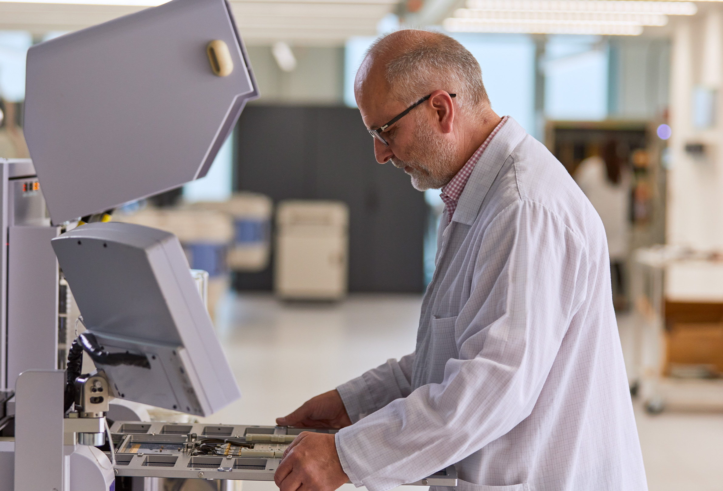 Zaměstnanec Apple v?bílém laboratorním plá?ti pracuje na technickém vybavení.