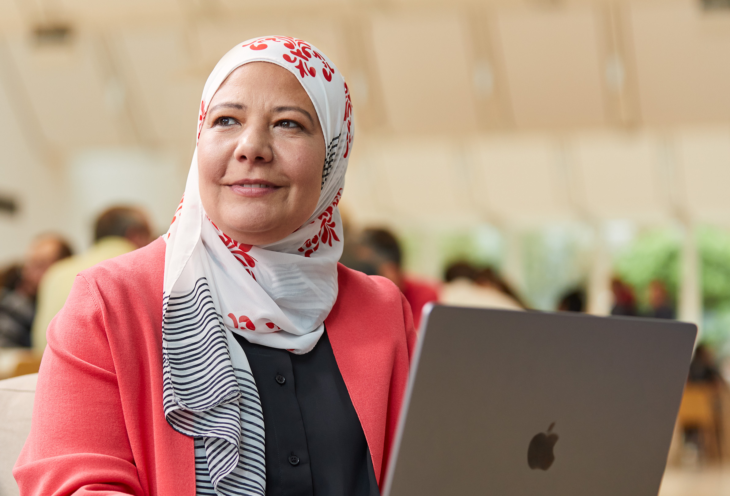 Zaměstnankyně Apple sedí, dívá se doleva a?p?ed sebou má MacBook.