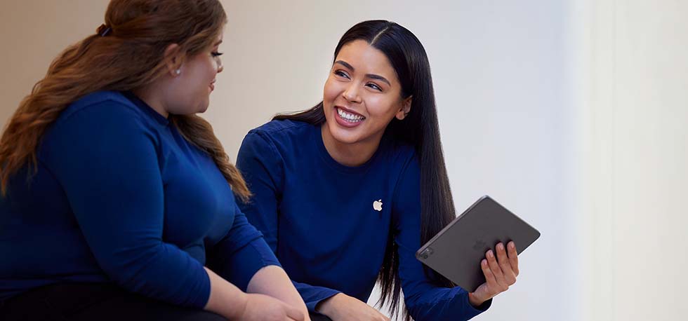 Carissa, un iPad à la main, discute avec une collègue de l’équipe Apple?Retail.