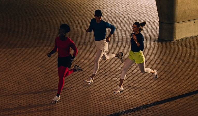 ?ena má nasazené Apple Watch Series 11 a protahuje se na podlaze, na obrazovce je Cvi?ení, Vychladnutí, Aktivita, Krou?ky aktivity