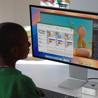 En kvinne jobber i et Excel-regneark p? en Mac, sittende ved et arbeidsbord. Excel-regnearket er sporer salget for fjerde kvartal. Bak Excel-vinduet er det et Pixelmator Pro-vindu.