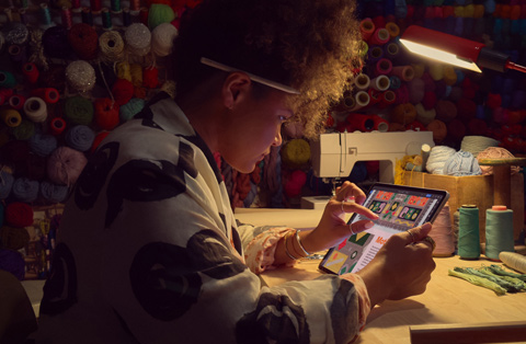 En person sitter ved et skrivebord og bruker to fingre til ? zoome inn p? en iPad-skjerm.
