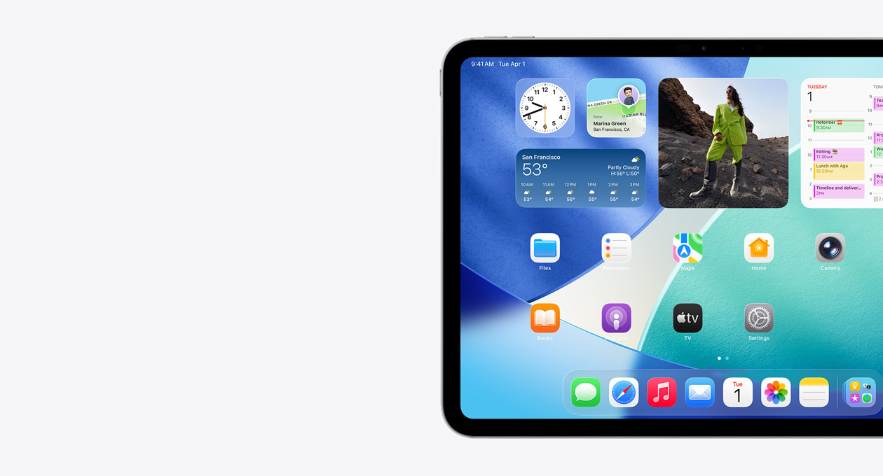 Un iPad, orientation paysage, c?té gauche de l’écran uniquement, l’écran d'accueil avec des widgets superposés, notamment une horloge translucide à effet Liquid Glass, l’app Localiser et le widget Météo, deux rangées d'apps plus petites et le Dock