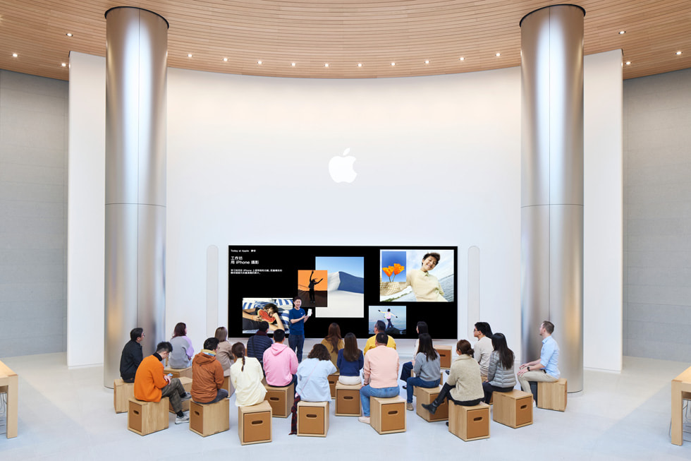 Hình ?nh khách hàng ?ang ng?i quanh m?t màn hình l?n trong phiên Today at Apple.