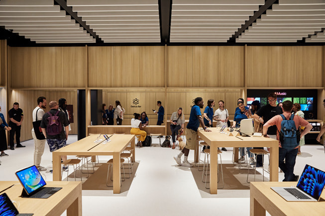 ?nh ch?p bên trong m?t ??a ?i?m Apple Store, trong ?ó khách hàng và nhan viên ?ang t??ng tác.