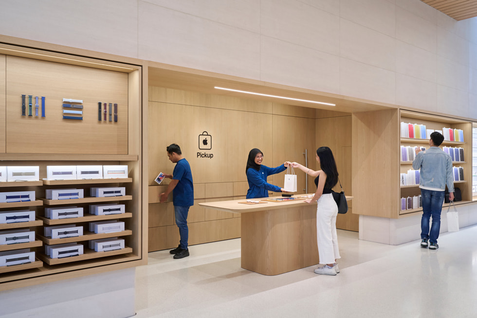 Dua anggota tim membantu seorang pelanggan di area Apple Pickup di dalam Apple The Exchange TRX.