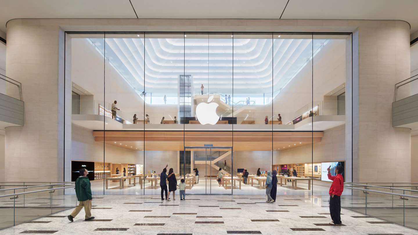 Foto pelanggan yang berdiri di depan pintu masuk interior Apple The Exchange TRX.