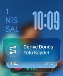 Birbirinden yava??a uzakla?an ü? Apple Watch modeli; ortadaki Siyah Trail Loop kordona sahip Natürel Titanyum Apple Watch Ultra 2'nin kadran?nda foto?raf g?rünüyor, sonra ekranda Ak?ll? Gruplama ipucu olarak kü?ük bir Geriye D?nü? simgesi beliriyor, Geriye D?nü? ekran? a??l?yor, yukar?da Liquid Glass saat rakamlar? g?rünüyor; sa?daki Deniz Ye?ili ?rgü Solo Loop kordona sahip Simsiyah Apple Watch'un kadran?nda Büyükanne adl? ki?iyle Canl? ?eviri ?zelli?i kullan?larak yap?lan bir konu?ma g?rünüyor; soldaki Koyu Turuncu Spor kordona sahip Gümü? rengi Apple Watch'un kadran?nda Antrenman uygulamas?nda Ko?u (D??) yaz?s? ve oynat dü?mesi g?rünüyor