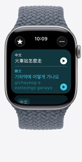 Apple Watch Series 11，展示太空灰色鋁金屬錶殼，搭配錨藍色編織單圈錶環(huán)，螢?zāi)簧系姆g app 顯示要怎麼去火車站的韓文翻譯和發(fā)音