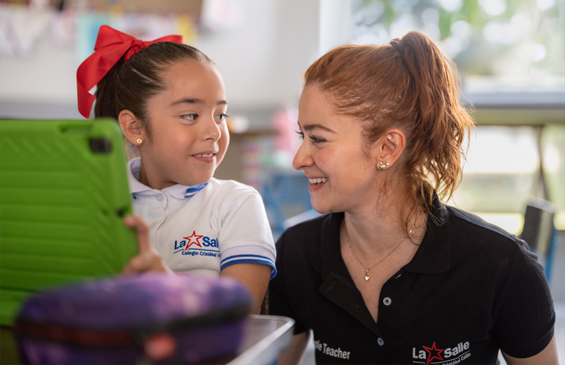 Eleane Ruth Guzmán Padilla shares a moment with a student in the classroom at Colegio Cristobal Colón.