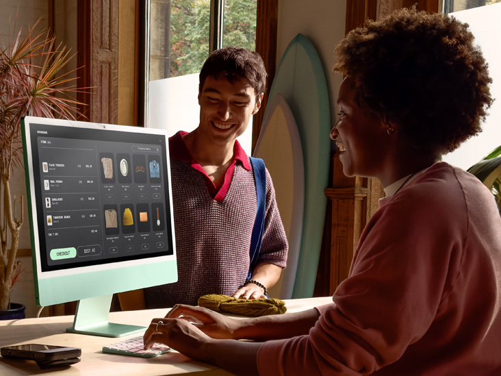 Dos personas en una habitación muy iluminada, una está revisando un pedido en un iMac verde con chip M4.