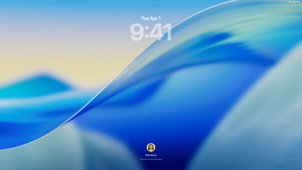 Three Mac models facing forward in a row gently pull away from each other: 16-inch MacBook Pro in Silver at left with the Phone app on screen showing recent contacts; 24-inch iMac in Blue in centre, a wave within the macOS Tahoe wallpaper moves on screen; 13-inch MacBook Air in Midnight at right, screen shows Spotlight Search over the desktop with Liquid Glass versions of the Dock and various widgets such as Calendar, Clock and Weather