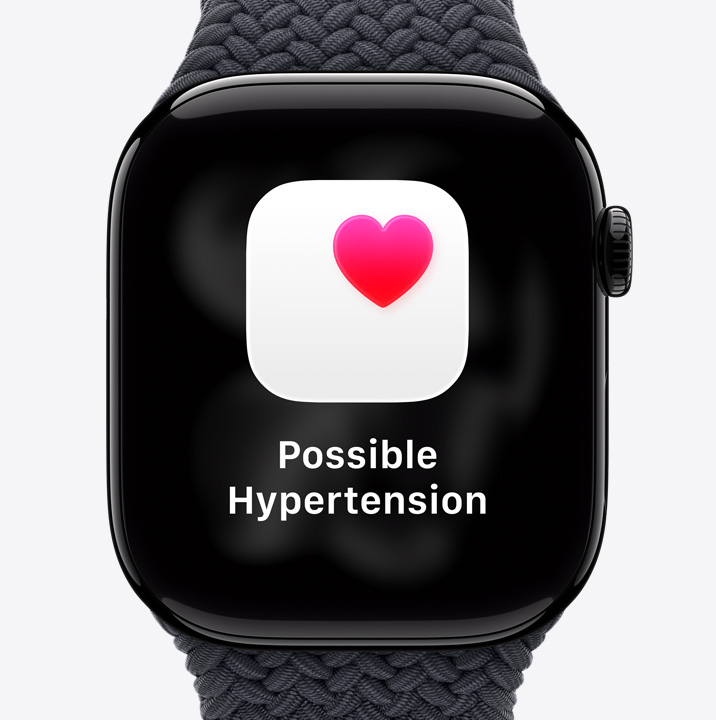 Apple Watch Series 11, pouzdro z le?těného klavírně ?erného hliníku, zdravotní oznámení o mo?né hypertenzi, r??ové srdce na bílém poli, na pravém boku korunka Digital Crown, sportovní ?emínek, ?erná barva