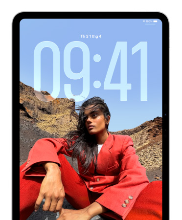 iPad hi?n th? Màn Hình Khóa(chǎn), trong ?ó các ch? s? l?n ch? th?i gian xu?t hi?n phía sau ?nh m?t ng??i ?ang ng?i